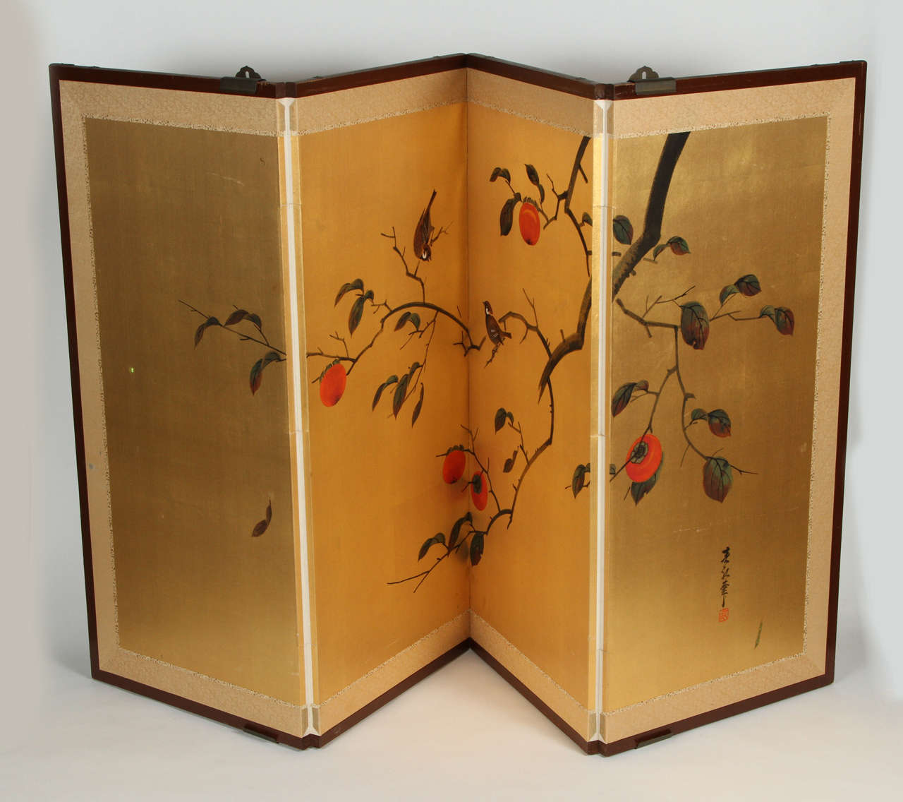 Vintage hand painted Japanese screen with birds and a persimmon tree. The image is painted on paper with ink and mineral color on a large field of gold leaf. There are four panels that fold to the size of one (16.5