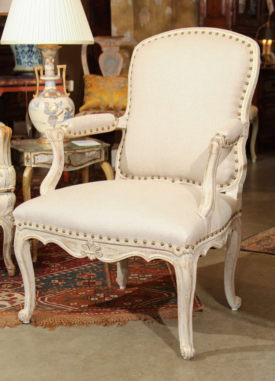 A 19th century Louis XV style painted armchair upholstered PLACE fabric linen with antique brass nail head.