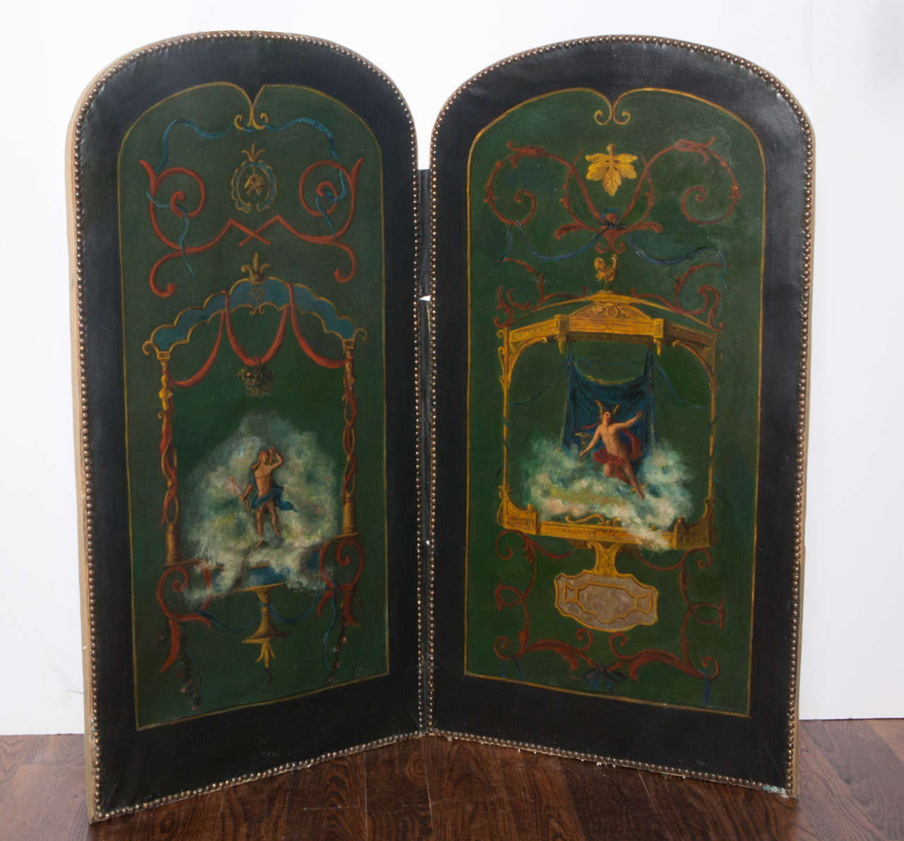 Two panel folding screen with oil paintings depicting mythological male figures.  Back of screen is upholstered in silk damask.  Brass nailhead trim.  Fabric hinges.