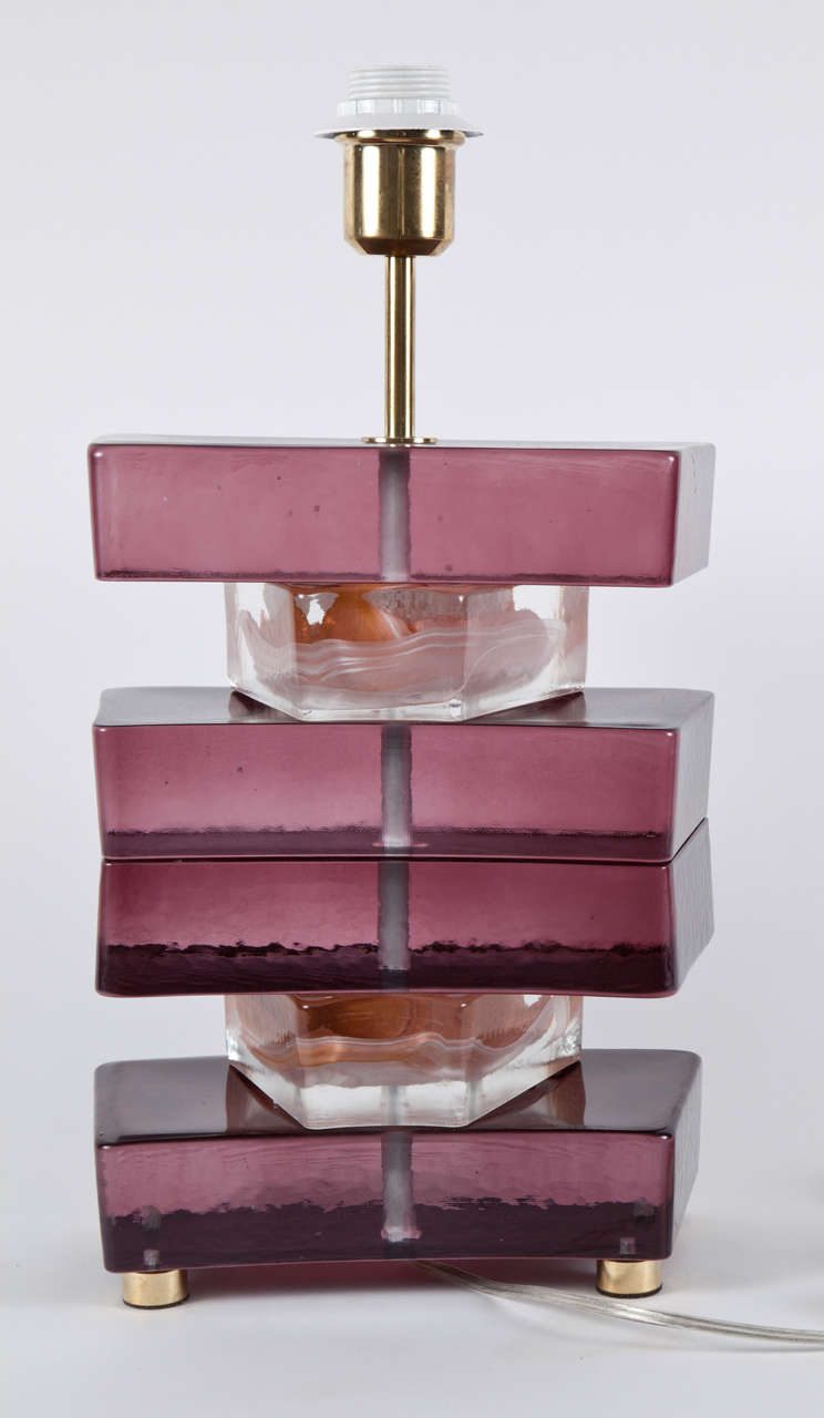 Fantastic pair of stacked glass lamps in amethyst/cranberry slabs and clear with orange/white inclusion spacers resting on brass legs.