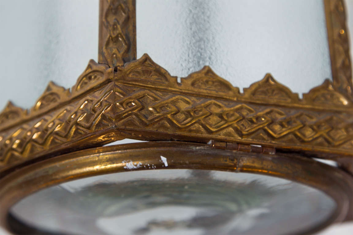 This elegant hexagonal brass lantern is embossed throughout and features wonderful detailing. The round handblown bottom glass is rimmed in brass and open downwards for easy access. Delicate in scale, this unusual piece would be charming in a small