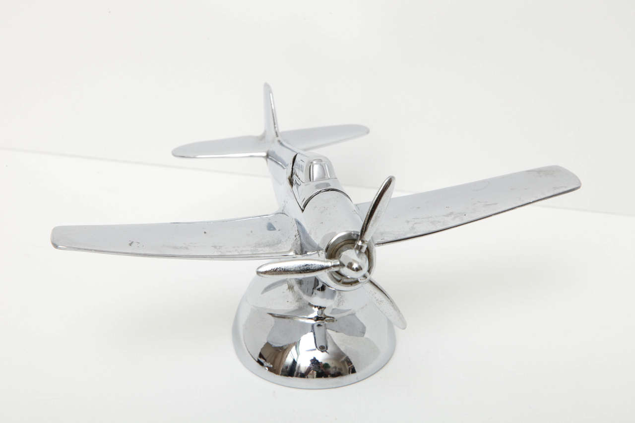 A novelty lighter in the form of an airplane. Chrome plane has a rotating propeller which when turned, releases the lighter from the cockpit. Marked 