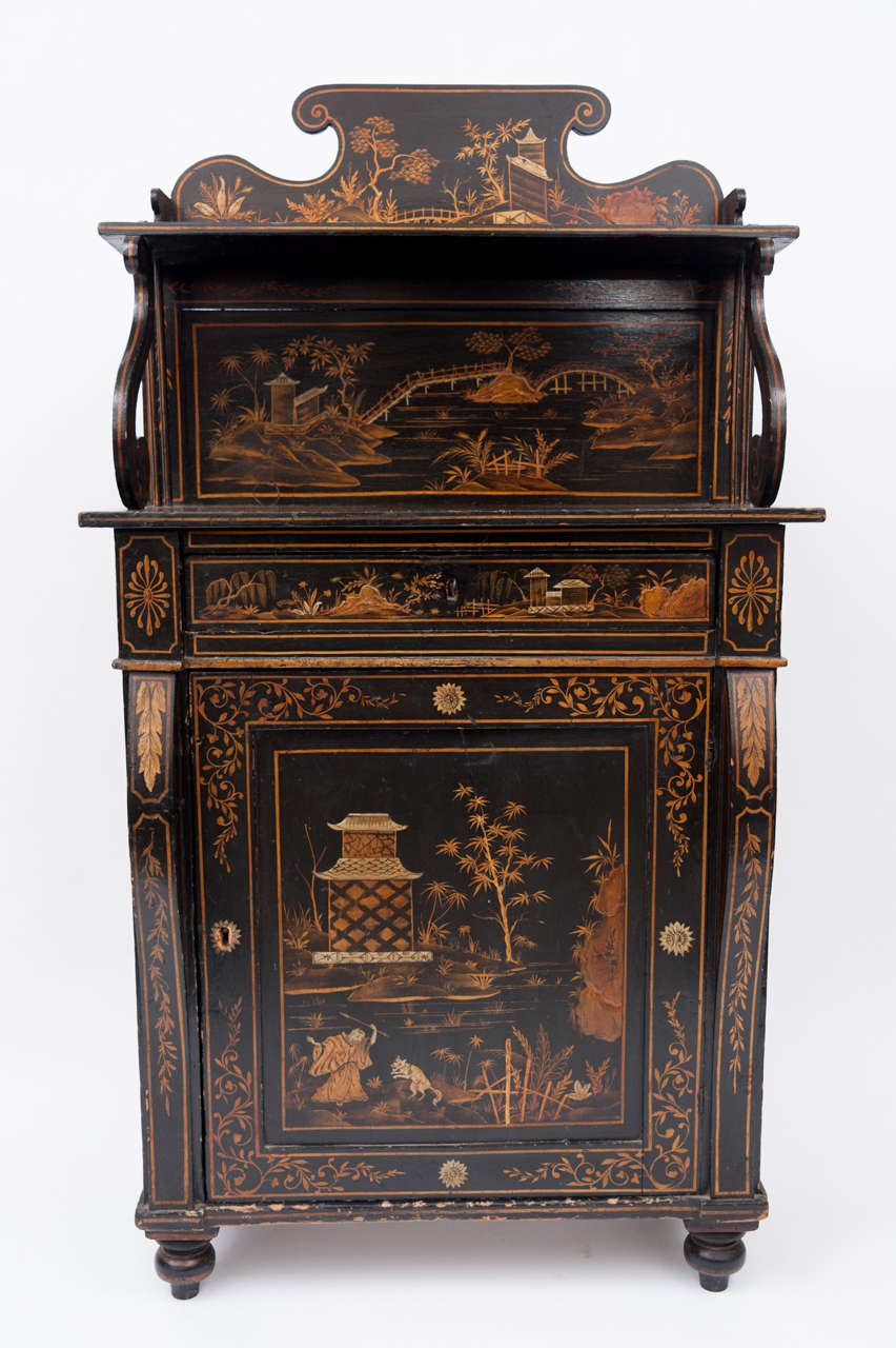 Regency black and gilt lacquered chiffonier of small proportions, the shaped super structure with 's' scroll supports with frieze drawer below; the single door flanked by scrolled pilasters raised on turned feet.  The whole beautifully decorated