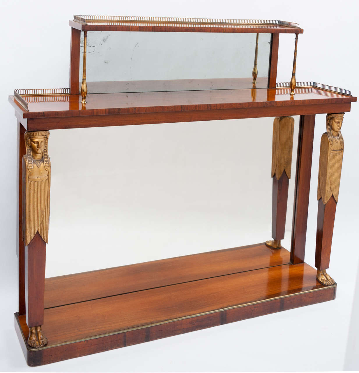 A good Regency rosewood and gilt console table, the rectangular super structure with a mirror back and pierced brass gallery, supported on gilded brass columns. The top also with brass gallery, supported on tapering pilasters with carved gilt wood