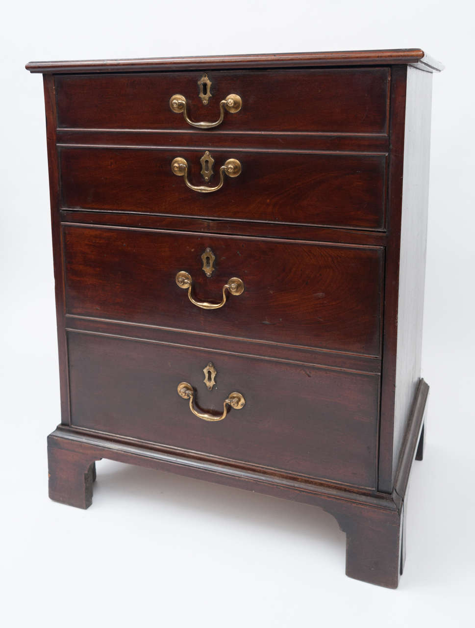 Geo III mahogany bedside cabinet or commode fashioned as a small chest of drawers, with good colour and original swan neck handles. The two top dummy drawers folding down to reveal compartment; and the two bottom dumy drawers pullout or pull-out for