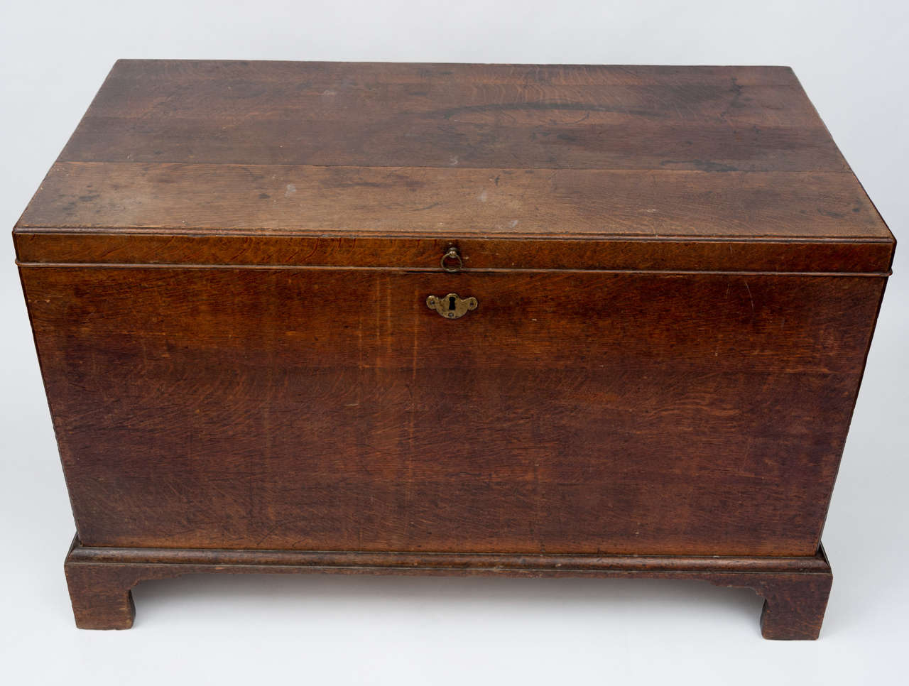 Geo II country house oak silver chest of restrained form, with large brass carrying handles. The top and corners with a moulded edge. Raised on original bracket feet. The interior still retaining its original oak and baize lined lift out trays.