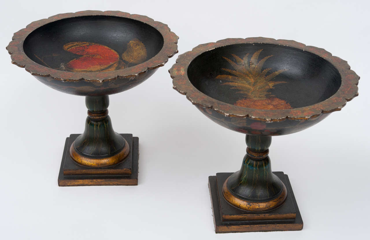 A very decorative, early C19th pair of carved wood French tazzas / urns / fruit bowls, with original painted decoration.  The circular tops with a serrated edge painted with trailing flowers; the interiors, one painted with a pineapple and the other