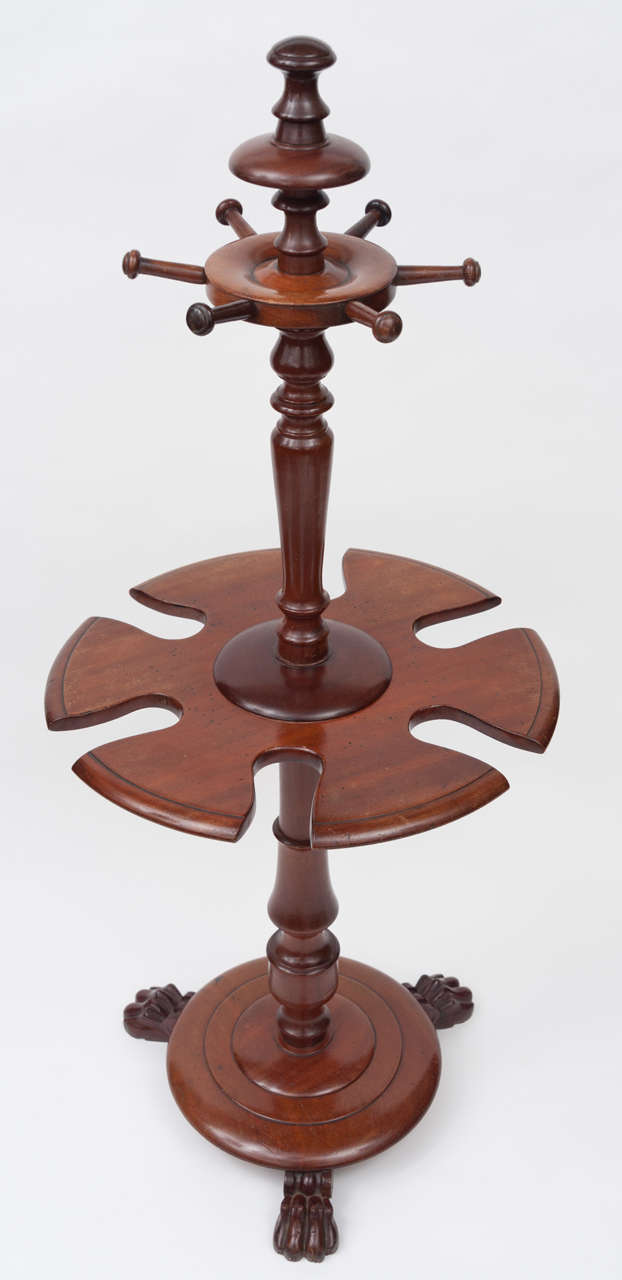 George IV mahogany boot and crop stand, the top section with 6 turned pegs to accommodate riding crops or hats, with a turned column down to a revolving tier to accommodate 3 pairs of boots.  Raised on a platform base with three carved paw feet.