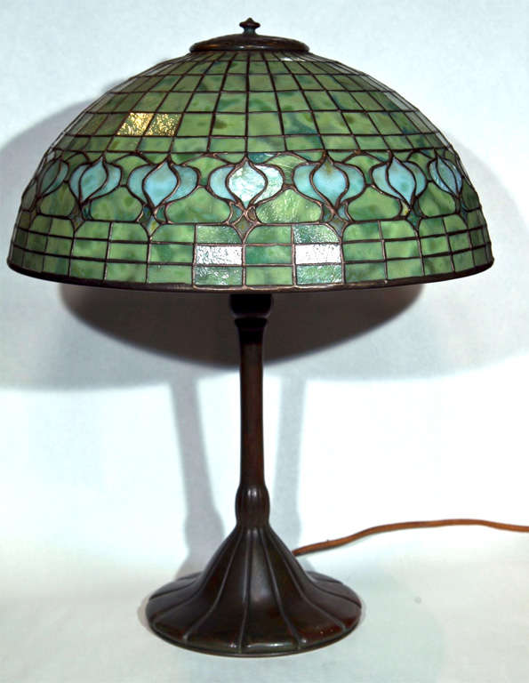 A period Tiffany Studios “Pomegranate” leaded dichroic glass lampshade on a heavily patinated, tapered bronze base. This beautiful lamp features a gold design on a heavily mottled field with a predominantly green into yellow tones. Circa 1900. Shade