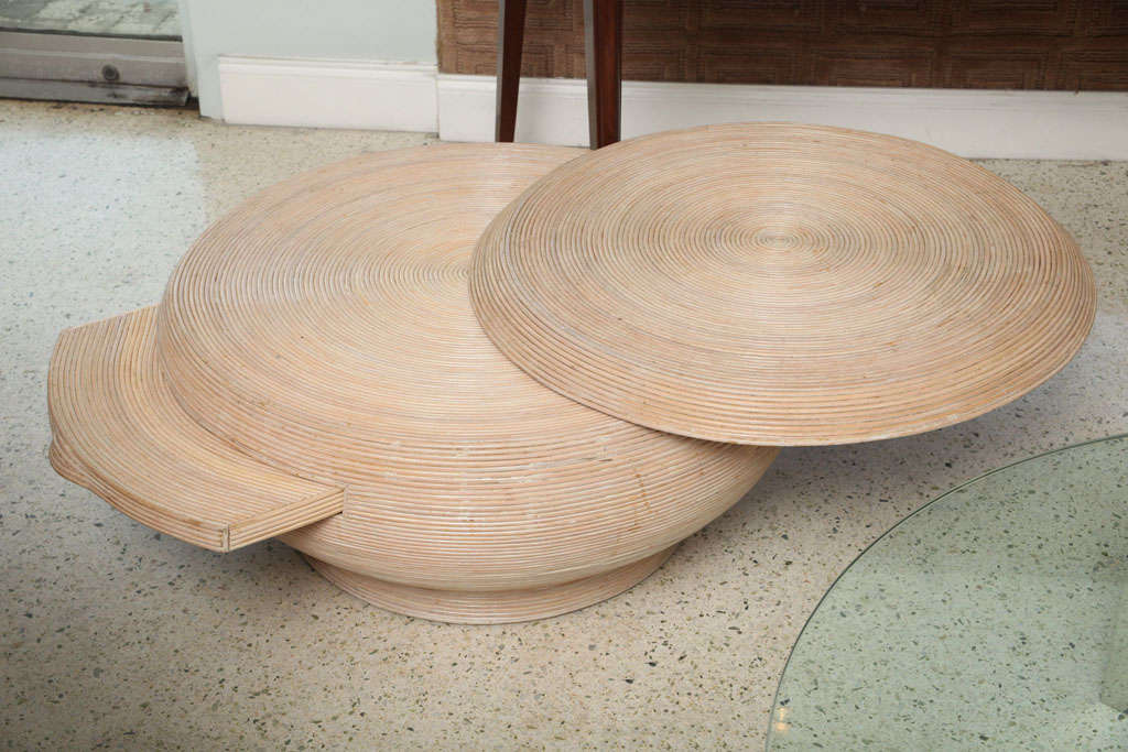 The circular top with pivoting arc revealing a secondary base, and a concealed slide drawer. Note length of table is in open position, diameter is closed. Rattan has a whitewashed finish.