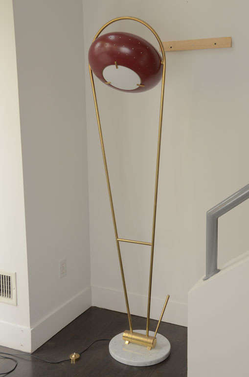 Originally designed by Angelo Lelli for Arredoluce, this floor lamp pivots on its brass armature front to back using the lever near the marble base. The red enameled light shade swivels and can be adjusted and its light directed as desired.