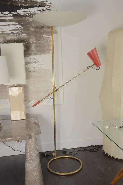 The striking design of this floor lamp starts with its round tubular brass base from which the brass pole supports not only one adjustable brass arm with red enameled light shade but a beautiful off white enameled brass dome light which directs