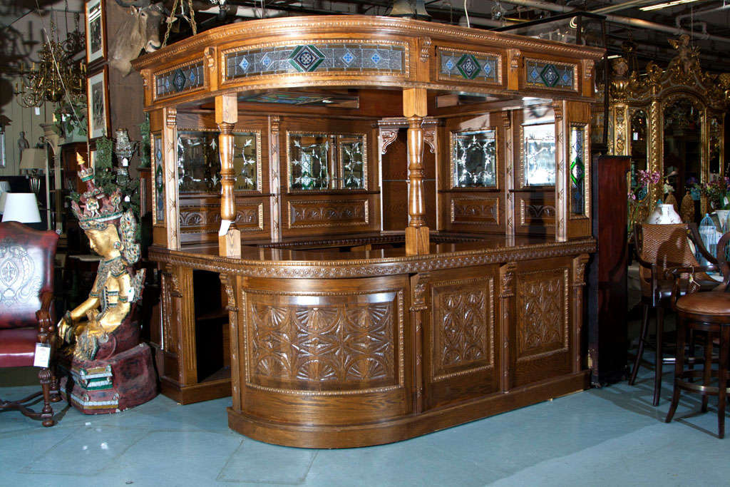 Beautiful oak corner bar.  Palatial looking.....Hand carved panels with stain glass and etched glass mirrors.  Bar has sink and electrified down lights to enhance its appearance. Excellent condition...ready to serve...