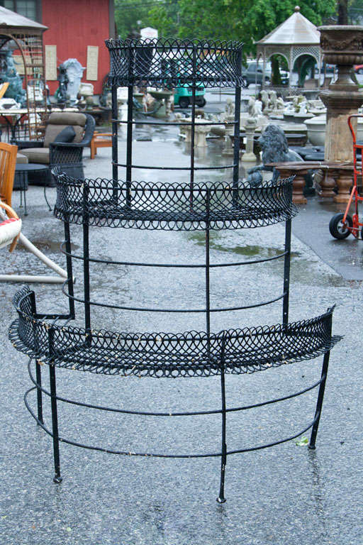 Turn of the century skilled craftmanship.  The Victorian iron demi-lune shaped stands have three platform tiers.  The pieces are adorned with depictions of lattice gating around the demi-lune edges.  A real treasure to have a pair to show off your