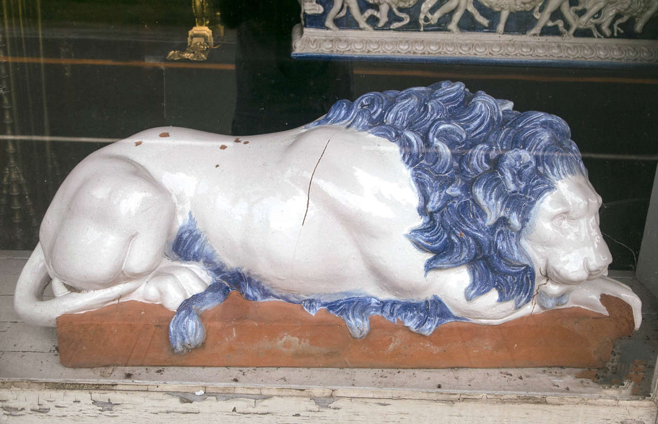 This pair of Italian made, sleeping lions, were made in the mid-20th century. They are of solid terra cotta and glazed in blues and whites, with surface crackling and cracks to simulate older models. There is some chipping to the white glaze on