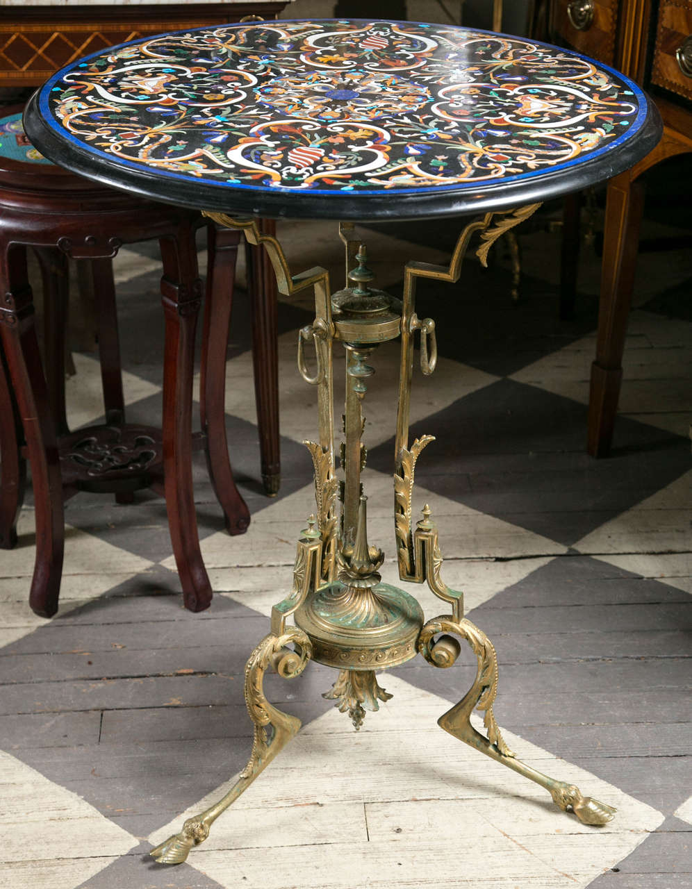 A bronze table base dating from the Victorian period.  Three supports on the top,  three legs decorated at the top with a swirl around rosettes, rings,  and leaf form below. A central finial above a swirled urn shape with a decorated bronze support