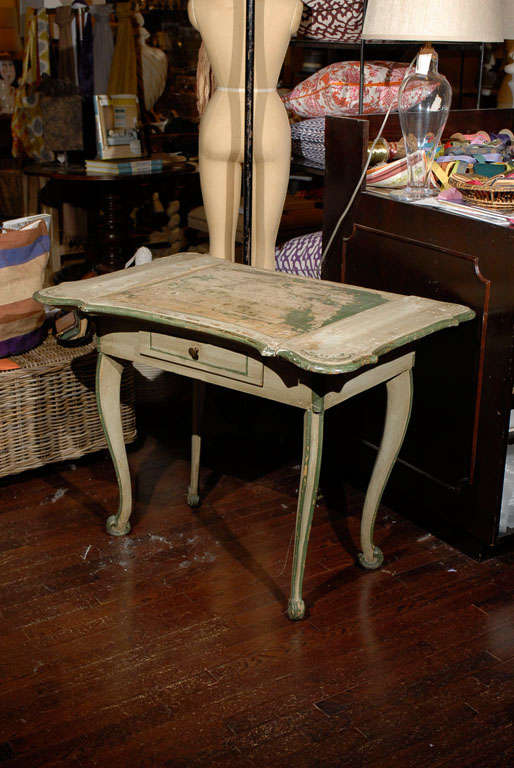 Italian 19th Century painted dressing table with worn green and grey paint.  Beveled and scalloped apron.  Center portion lifts.  Case holds one drawer.  Resting on carved cabriole legs and scroll feet.