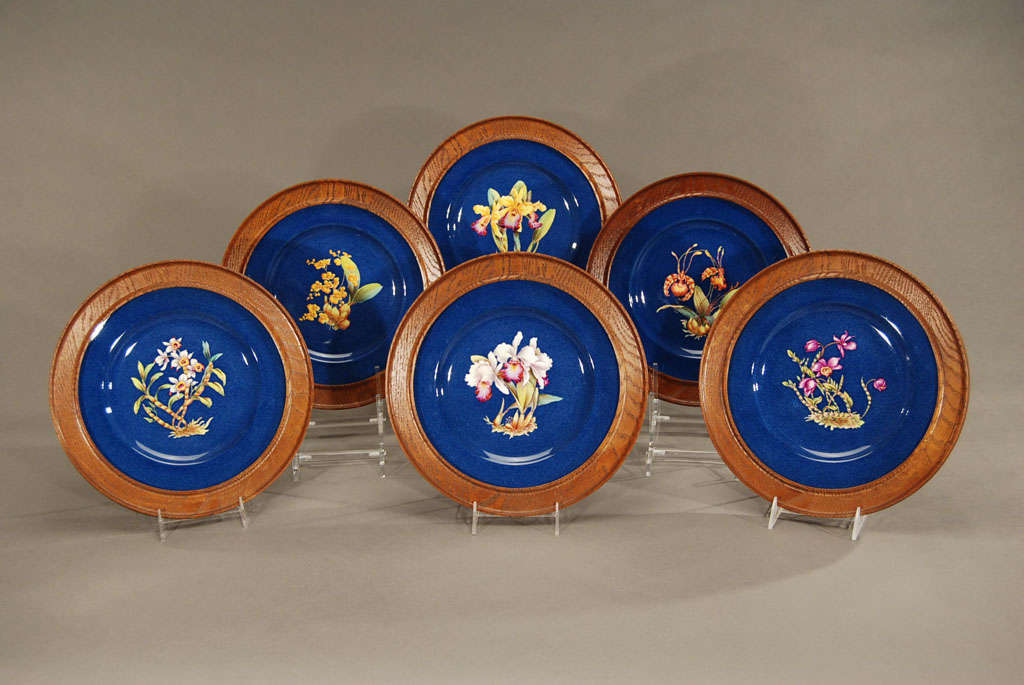 This set of 12 Copelands Spode dinner sized plates are made for Tiffany and each is mounted in a custom oak frame. They can easily be removed and used as dinner or service plates or hung as is, to create a vibrant botanical display of orchids. Each