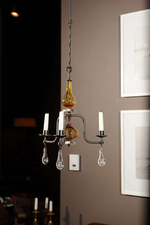 Chandelier with three arms for candles. Hand-forged frame made by Boda steel works, glass made by Kosta Boda. Bottom pendants with motifs of faces.