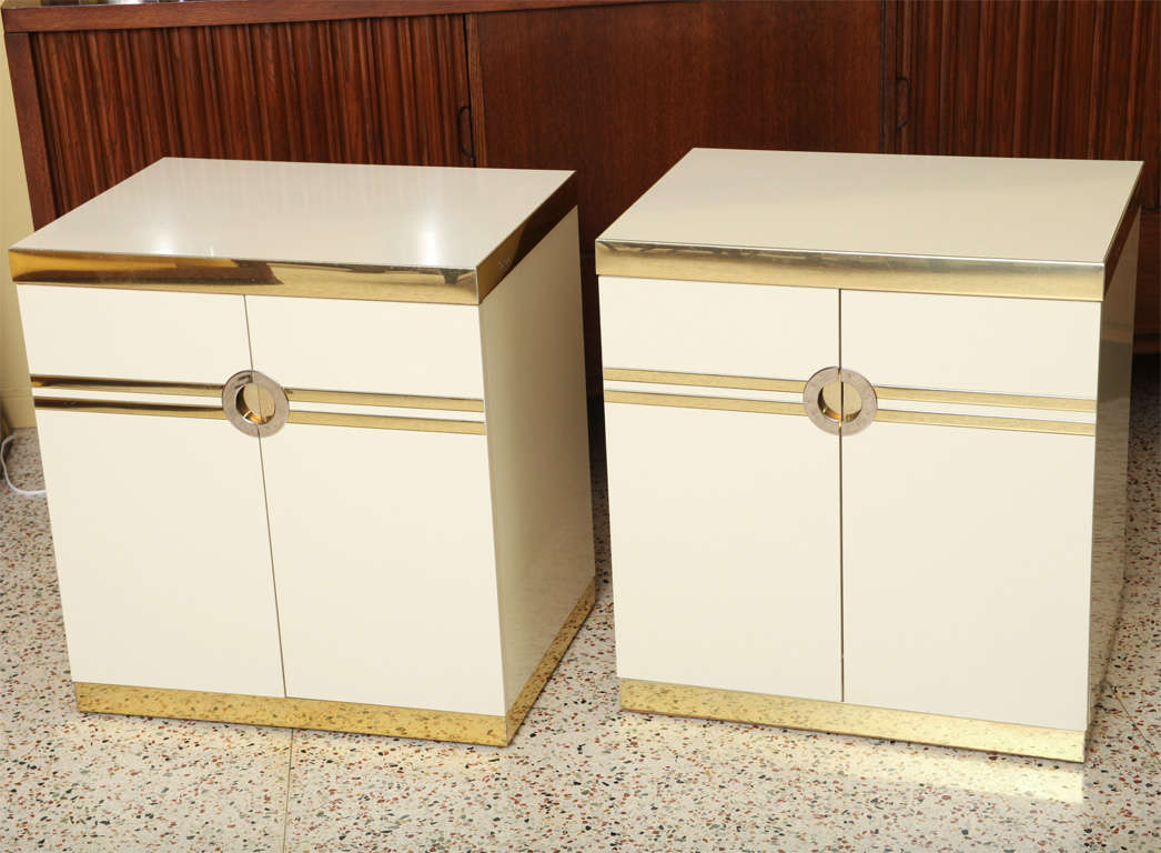 SOLD  Sleek & modern Pierre Cardin designed & signed pair of cabinets of metal trimmed white laminate with centered circle recessed nickel pulls. Two doors on each open to four drawers. Brass anodized aluminum banding to the the top edge and plinth