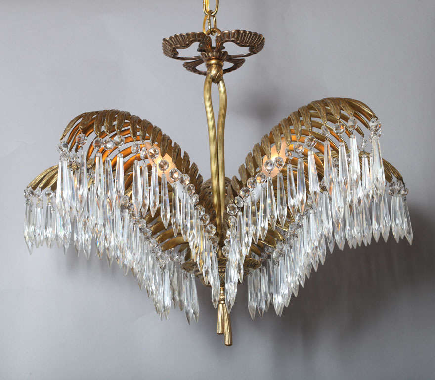 Fine chandelier of gilt brass, having three palm fronds embellished with hanging crystal pendulum prisms, surmounted by a ribbon, and finished with a chased bowl and tassels.