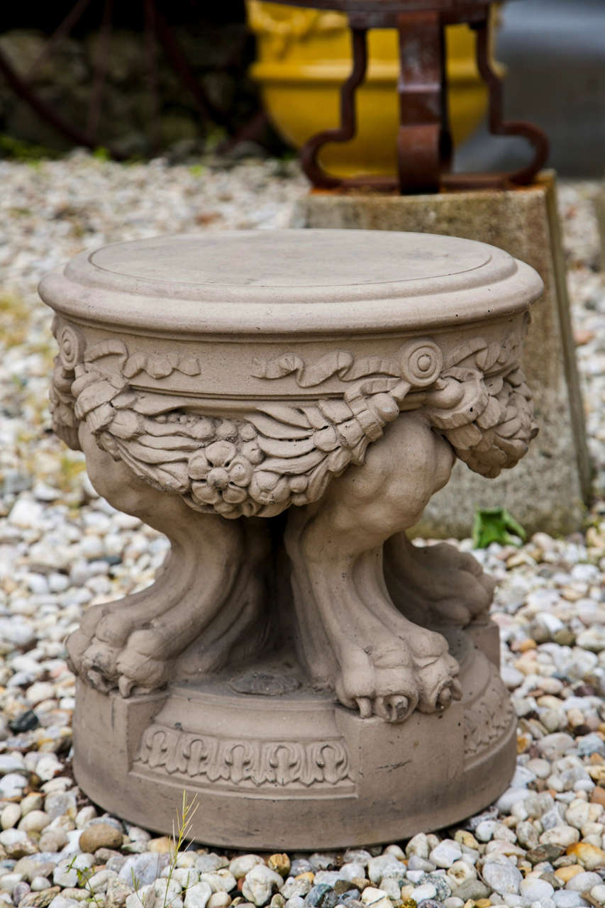 A terracotta neoclassical garden stool,  having draped garland and paw feet