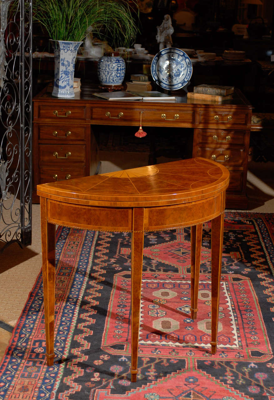 This lovely English vintage game table is made of burled walnut with satinwood inlay. On square tapered legs with boxwood stringing. The table top opens to a green felt lined game table top. One of the back legs pulls out to support the open top.