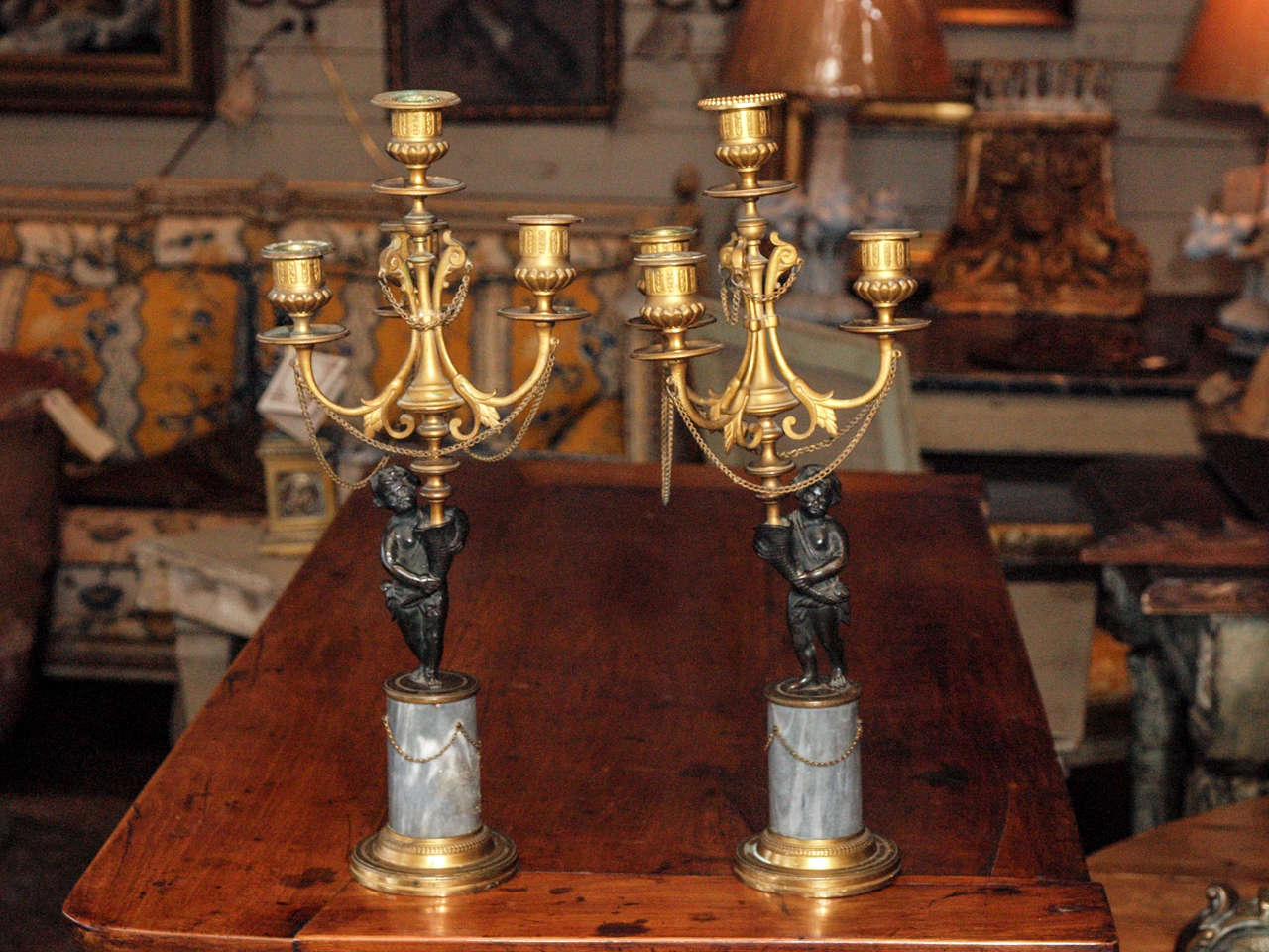 18th century pair of Louis XVI period patinated and gilt bronze candelabra. Each with a putti standing on a marble plinth with chains and holding a 4 light candelabra