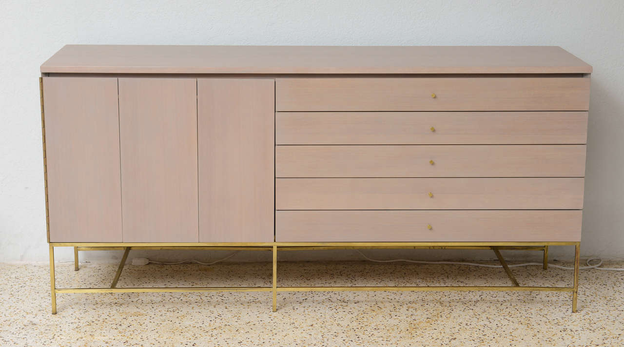 A bleached mahogany and brass credenza by Paul McCobb for Calvin. We've updated it here with our signature greige finish… absolutely gorgeous!