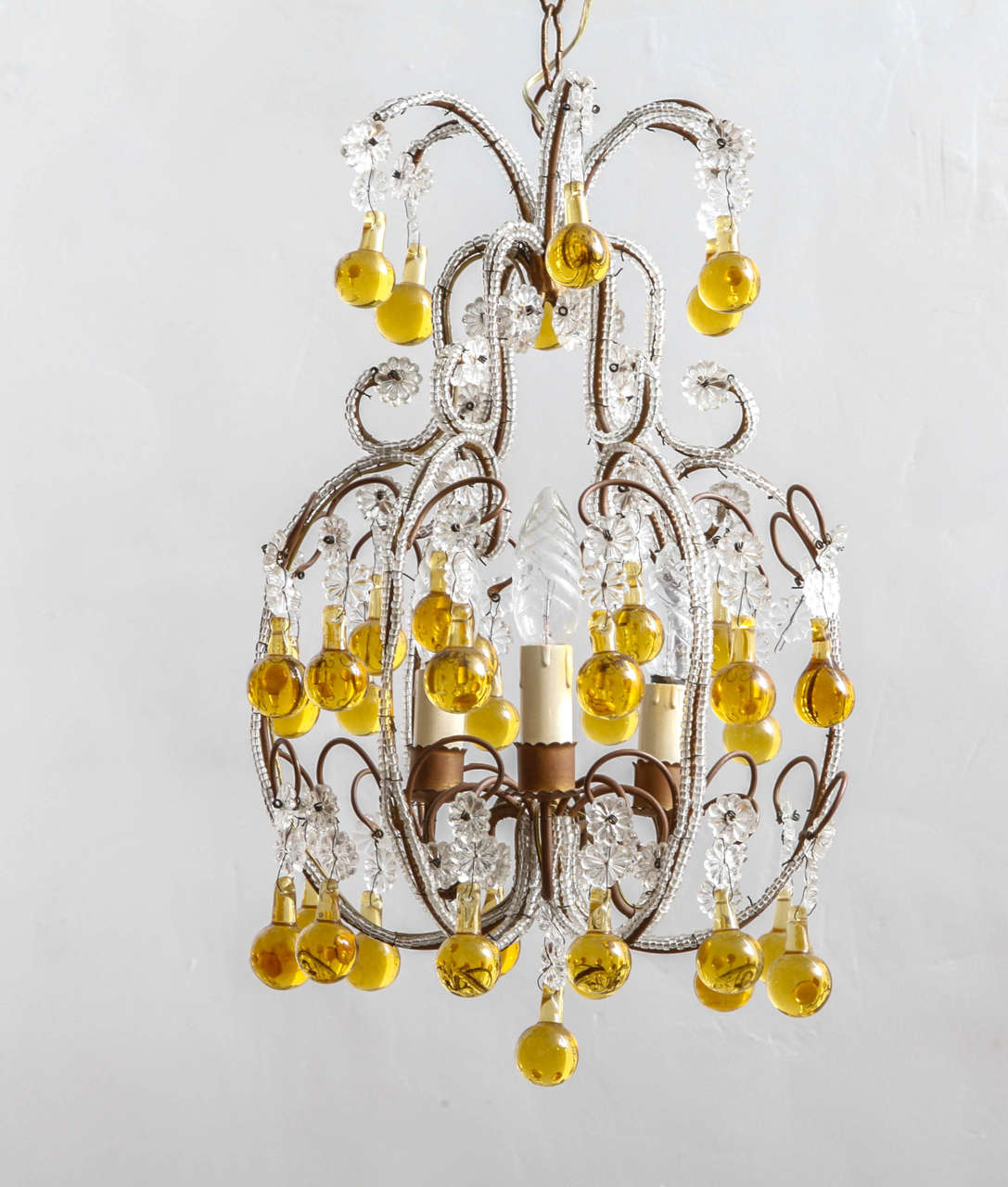 Lustre français en laiton et cristal, vers 1920. Verres en cristal clair et fleurs perlées le long d'une monture en laiton avec de grosses gouttes de larmes jaunes.