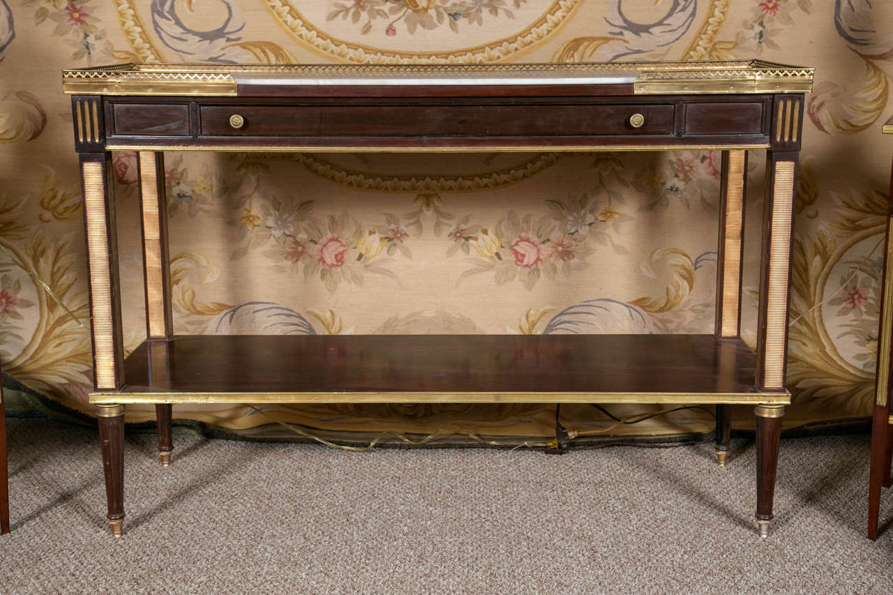 Russian neoclassical marble-top console table. Tapering with cookie cutter inserts of bronze. The bronze sabots leading to a column continuation that holds an elongated drawer below a white marble top with greyish vein tones. The top with its marble