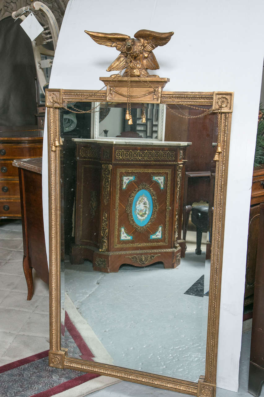Antique mirror with gilt carved eagle. This magnificent eagle is gilt and carved into a fine representation of freedom. It is carrying in it's beak a chain of tassels whilst standing on a platform above the middle of the mirror. Exquisite in detail