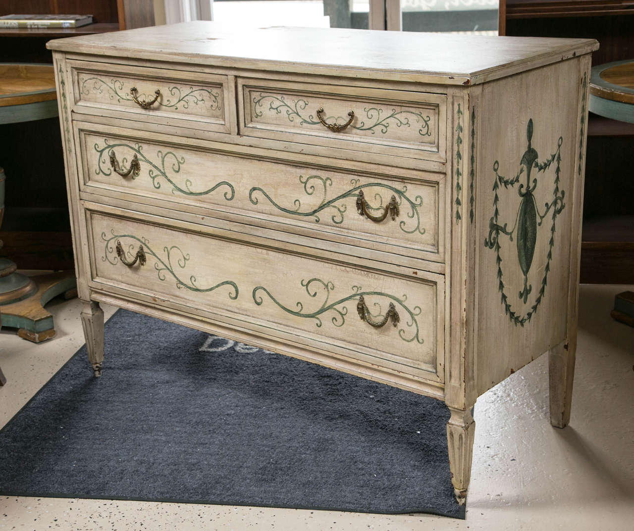 Adams style paint-decorated commode. Two smaller drawers atop two larger drawers. Each designed with scroll like blue/green vines. This masterful painted Adams Style Commode is finished in a warm cream color and decorated with a beautiful blue/green