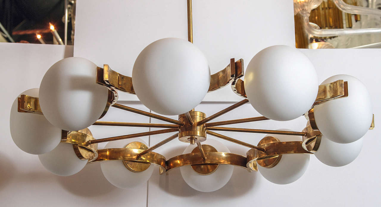 This Italian chandeliers, created in the style of Stilnovo, features a polished brass frame accentuated by large frosted white glass shades.