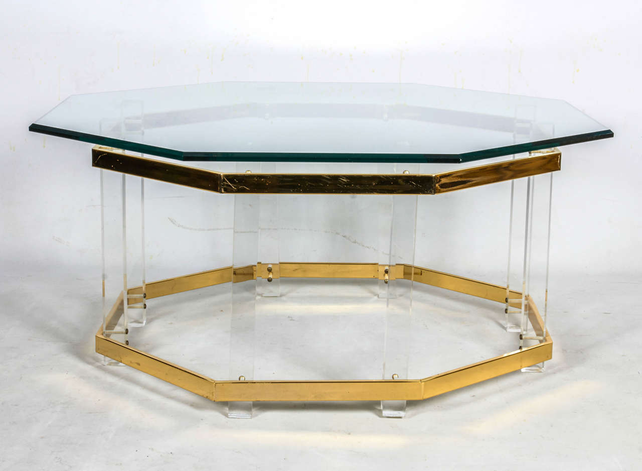 Octagonal coffee table with a beveled glass top over Lucite supports and brass trim. The glass top aligns with the octagonal base below. Please contact for location. 