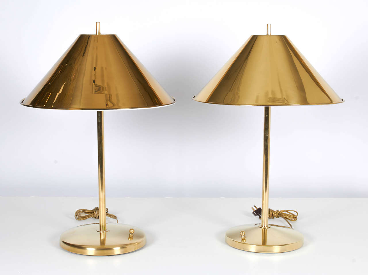 A beautiful and rare pair of brass Nessen lamps with gleaming, polished brass shades. Please note that the bases of the two lamps are slightly different: one base is a little wider than the other; and one base is a little more domed than the other