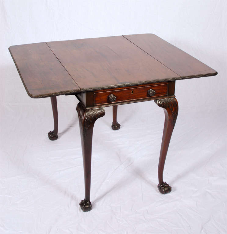 Mahogany drop leaf table with ball and claw feet, acanthus leaf carving at top of leg, and carved bead work along outer edge of table top. (43.75