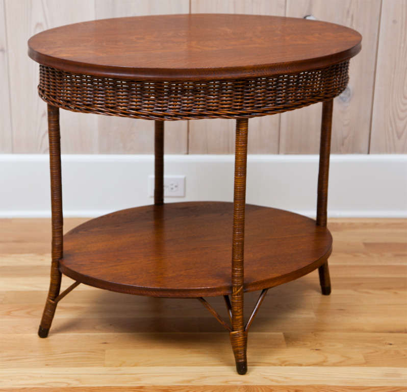 Antique wicker table with quarter sawn oak top and shelf and woven apron.