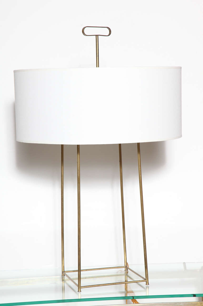 Rare, midcentury brass table lamp by Tommi Parzinger. Featuring an open, tapered box kite frame design with original brass Key finial. Two sockets. Two pull chains. New circular translucent light white linen shade. 24H to mid socket. Small