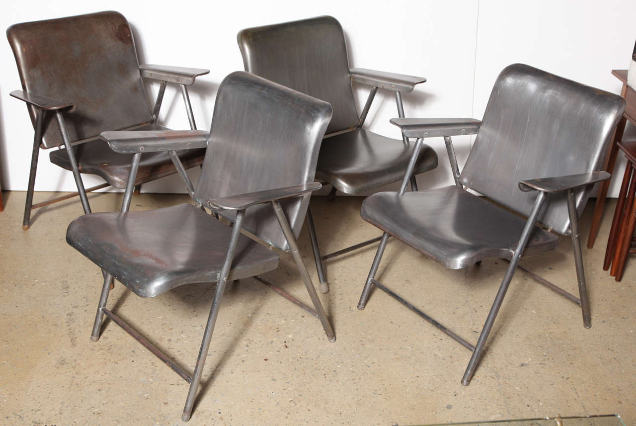 Four Industrial Modern Russel Wright Folding Arm Chairs from the 1940's. Featuring wide, lightweight, sturdy and comfortable design. Classic folding Porch Chairs in heavy gauge Steel. Easy to store. Paint removed and sealed