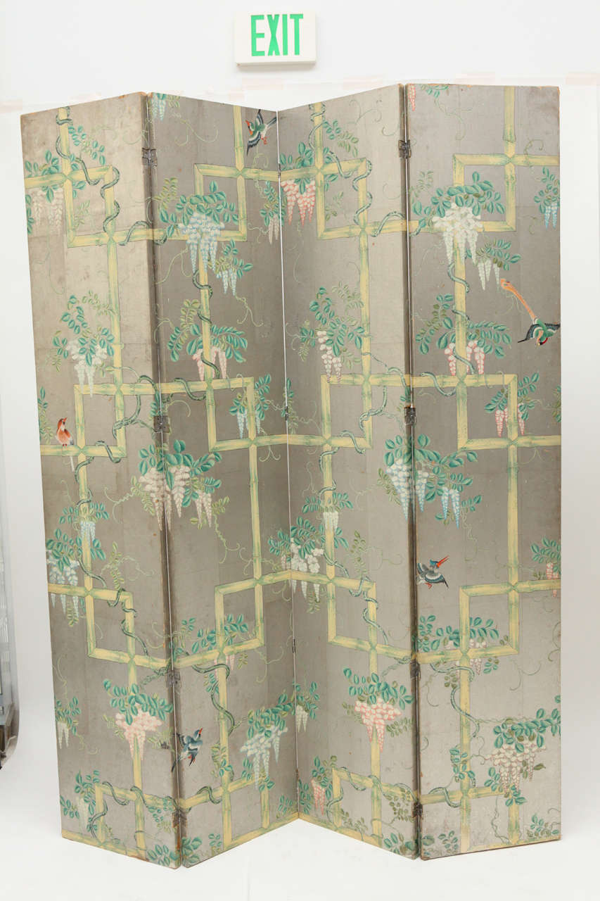 A lovely Chinoiserie folding screen with hand-painted tea paper on silver leaf, featuring birds and wisteria vines on a bamboo fretwork. The paper is reminiscent of a Gracie wallcovering. The back of the screen is also a hand painted paper.