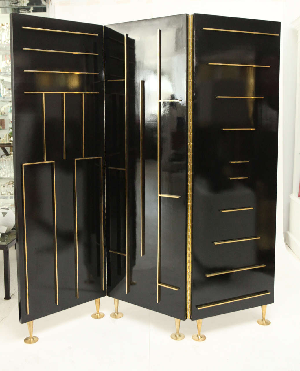 This striking and modernist three-panel screen finished in deep brown lacquer has raised brass patterning on both sides and is set on stylish brass feet.  Designed and manufactured by Frank Kyle of Mexico City this screen is a show stopper.