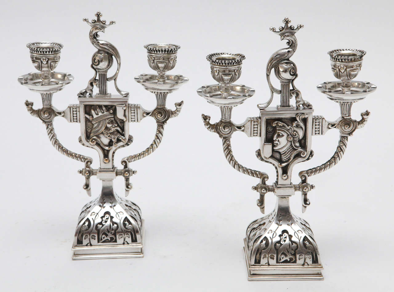 A beautiful pair of intricately detailed Renaissance style silver plated bronze candelabra. The candelabras features a double-sided central shield with a soldier on one side and a king on the other. There are a myriad of animals decorating the