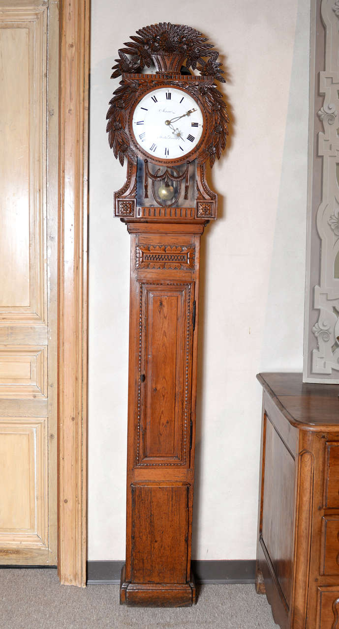 Here is a beautiful antique Normandy tall case clock in the Saint Nicolas style.  It is hard-carved in pine with a fine basket of flowers and leaves at the crown.  A few flowers can be found on the body as well other carved details.  The original