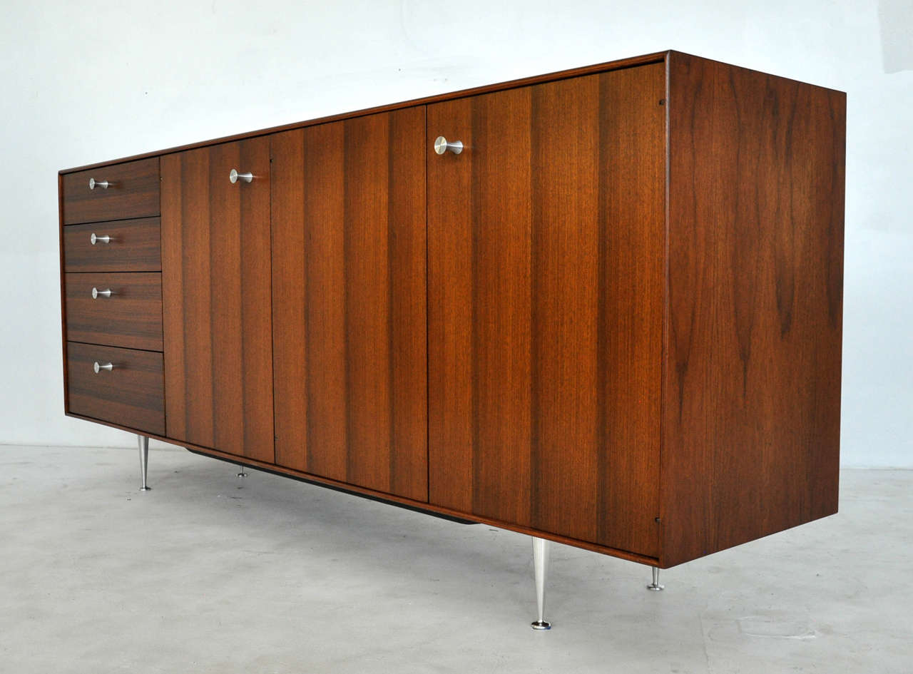 1950s thin-edge credenza by George Nelson for Herman Miller. Fully restored. Walnut case with new spun aluminum pulls. Early Herman Miller foil label inside drawer.