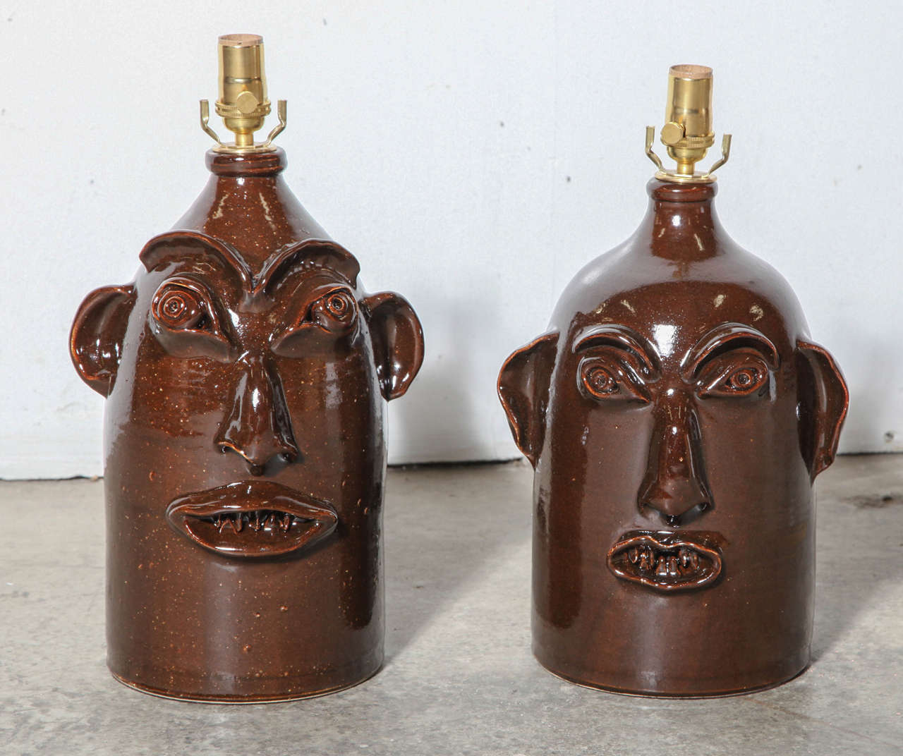 A pair of hand-thrown jug lamps with hand-detailed facial features added. Kiln fired, lead-free glaze. Height includes lamping.