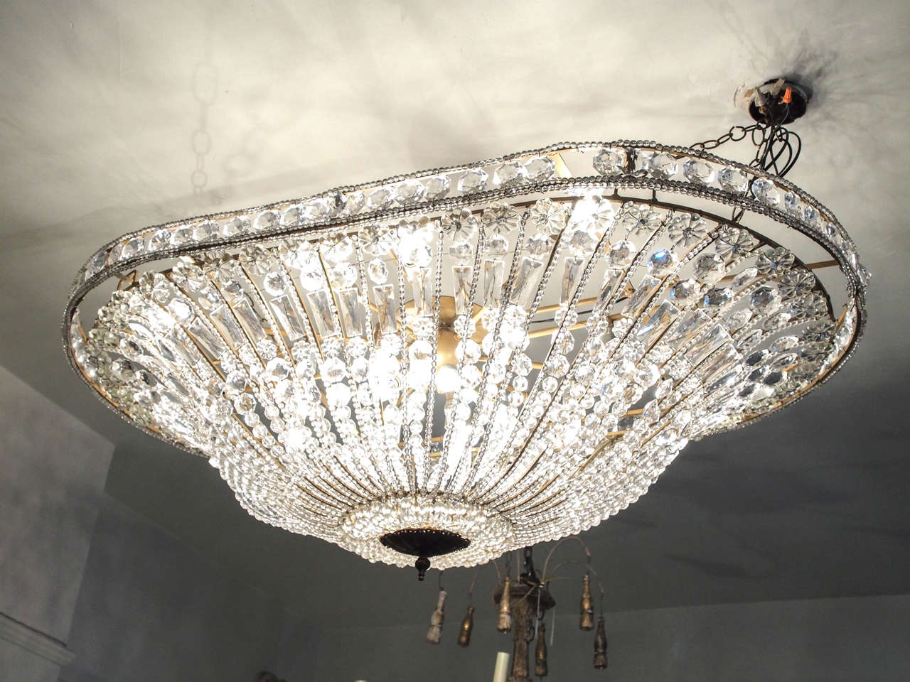 Late 19th century. Flush mount very large oval crystal and bronze chandelier. Empire style. Eighteen-lights. Crystals are beaded and attached to each rod. Comes from an old hotel in Paris. US wired.