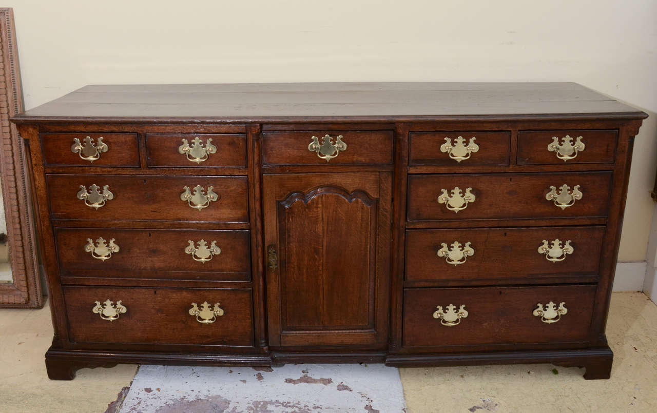 English  MID TO LATE 18TH CENT. PROVINCIAL OAK DRESSER BASE--WITH 9 DRAWERS CENTERED BY TOMBSTONE PANELED CUPBOARD DOOR-- QUATER COLUMNS AT ENDS & FLANKING CENTER DRAWER AND CUPBOARD DOOR