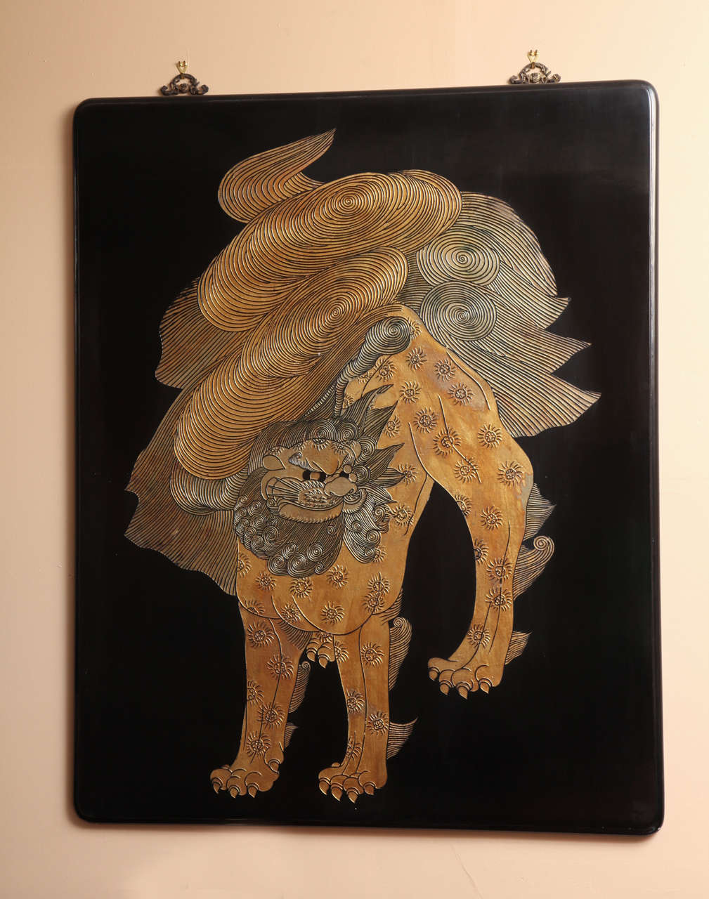 A Chinese carved and lacquered coromandel panel from the mid-20th century. Each panel features a typically Chinese stylized mythical guardian lion with gold leaf. The lion is lightly carved into the wood, with great attention paid to the delicate