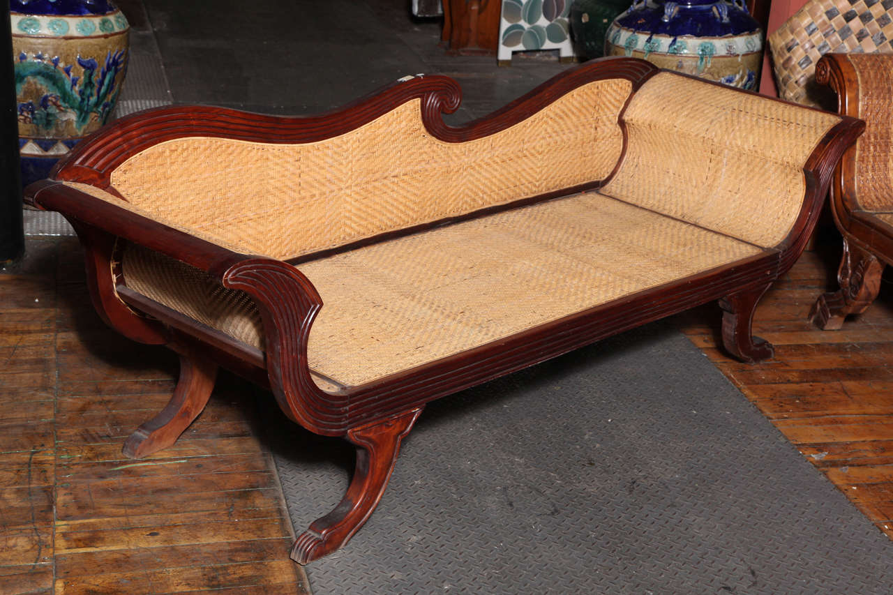 A Dutch Colonial carved teak sofa with rattan upholstery from the 1930s. Made in the Java during the first half of the 20th century, this elegant carved teak sofa features an exquisite curvy back, reminiscent of a delicate wave. The unusual